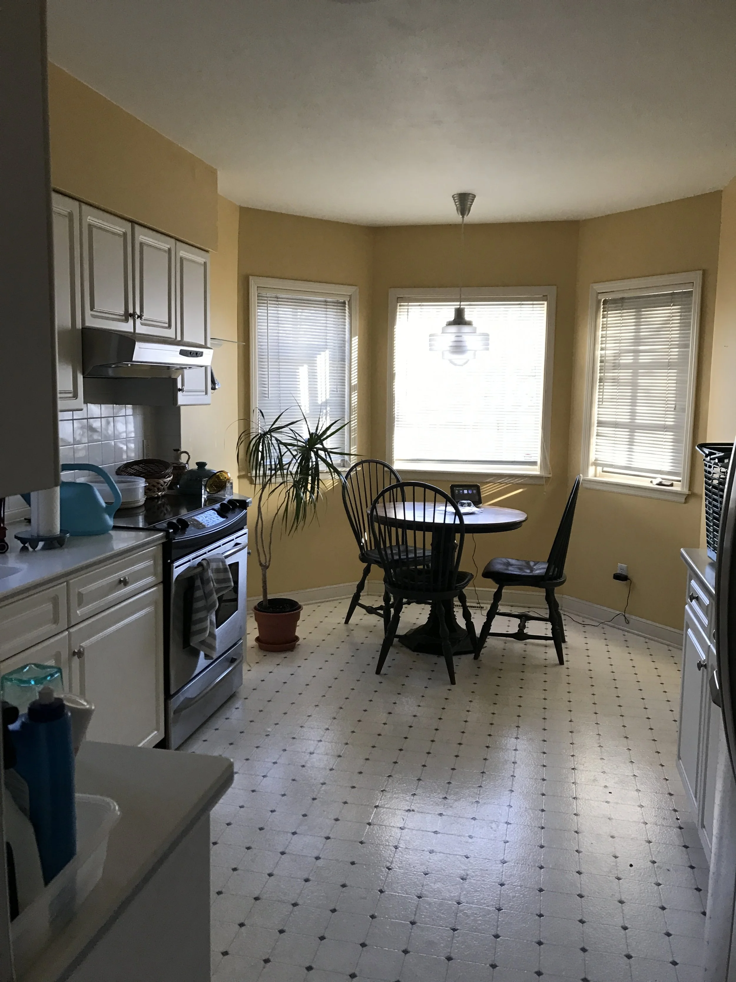 Bright breakfast nook with bay windows, round table and cheerful patterned tile floor